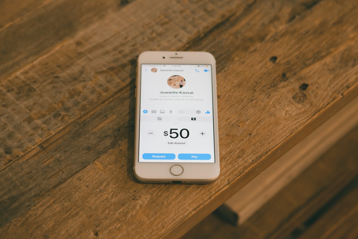 White smartphone displaying a payment application on a wooden table.